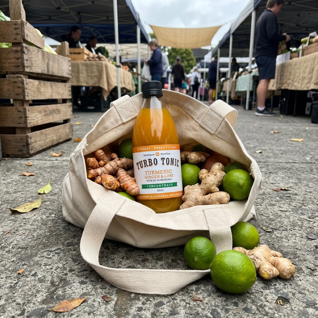 A Turbo Tonic bottle in a market tote with fresh turmeric, ginger and limes